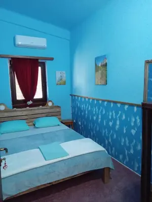 a blue bedroom with a bed and a window at Apartman Retro in Žepče