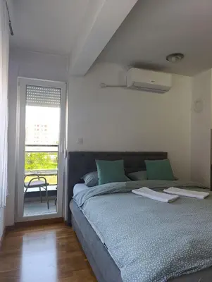 a bedroom with a large bed and a balcony at Apartman Dunja in Banja Luka