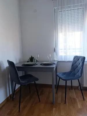 a dining room table with two chairs and a window at Apartman Dunja in Banja Luka