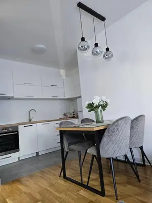 a kitchen with a table with chairs and a vase of flowers at A LUX APARTMAN Banja Luka in Banja Luka