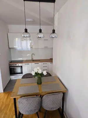 a kitchen with a table with a vase of flowers on it at A LUX APARTMAN Banja Luka in Banja Luka