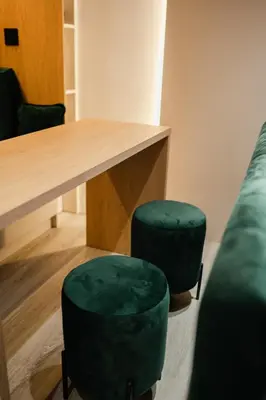 a room with a table and two green stools at Studio Compact in Doboj