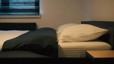 a bed with white sheets and pillows next to a window at IB Oil doo Restoran s prenoćištem in Cazin