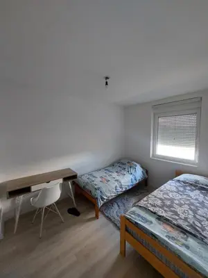 a bedroom with two beds and a desk and a window at Vista Bihać in Bihać