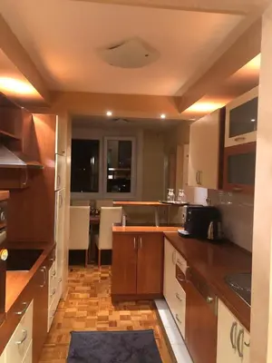 a large kitchen with wooden cabinets and a table at Apartman Mokusnice Zenica in Zenica