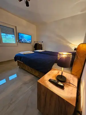 a bedroom with a bed and a table with a lamp at Skylight suite apartment in Tuzla