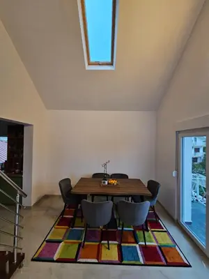 a dining room with a table and chairs on a rug at Skylight suite apartment in Tuzla