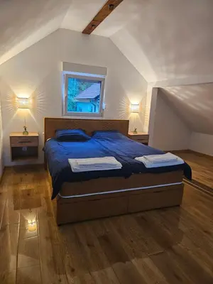 a bedroom with a bed with a blue comforter and a window at Skylight suite apartment in Tuzla