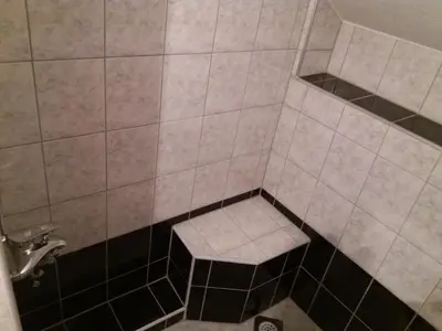 a tiled shower with a bench in the corner at Guest House Majstorovic in Banja Luka