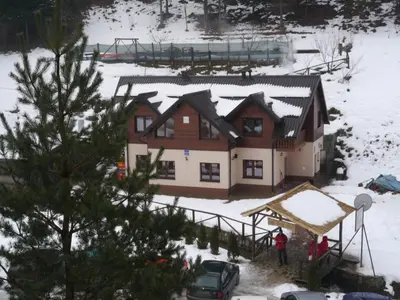 a house in the snow with a man standing in front of it at Motel Luka in Deževice