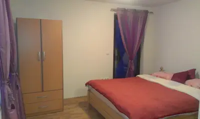 a bedroom with a bed and a dresser with purple curtains at Motel Luka in Deževice
