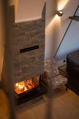 a living room with a brick fireplace and a chair at Vila Hill Rest in Visoko