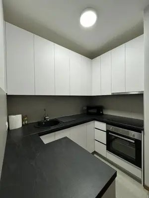 a kitchen with white cabinets and a black counter top at Apartman Blanka in Banja Luka