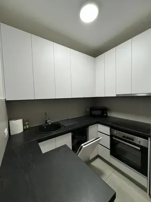a kitchen with white cabinets and a black counter top at Apartman Blanka in Banja Luka