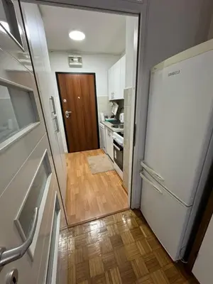 a kitchen with a white refrigerator and a wooden floor at Stan na dan in Zenica