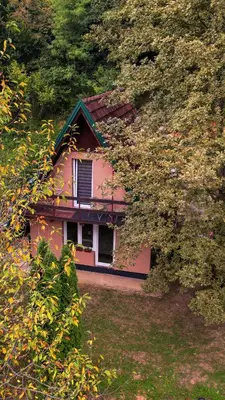 a pink house is seen through the trees at Studio apartman Farah in Bihać