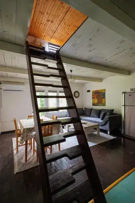 a ladder leading up to a living room with a table at Studio apartman Farah in Bihać