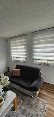 a living room with a couch and two windows at Apartman Deny in Sanski most