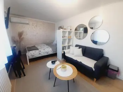 a living room with a couch and a bed and mirrors at Studio Apartman in Banja Luka