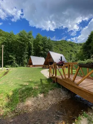 a wooden bridge over a field with two buildings at Plivska vila 1 in Jajce