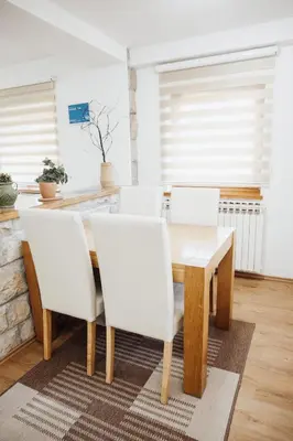 a dining room with a wooden table and white chairs at Ice Queen Vlasic in Šišava