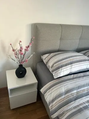 a bed with a vase with flowers on a night stand at Apartmani Kastel 1 in Banja Luka