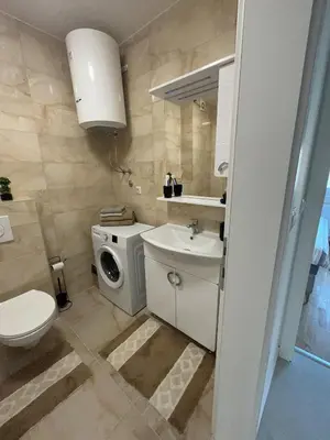 a bathroom with a toilet sink and a washing machine at Apartmani Kastel 1 in Banja Luka