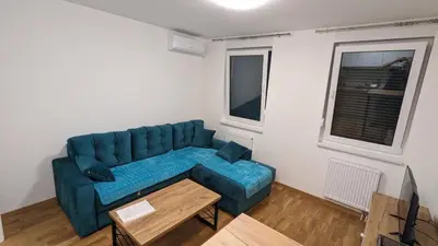 a living room with a blue couch and a table at Apartmani Kastel 2 in Banja Luka