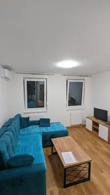 a living room with a blue couch and a table at Apartmani Kastel 2 in Banja Luka