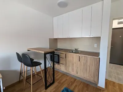 a kitchen with white cabinets and a table and chairs at Apartmani Kastel 2 in Banja Luka