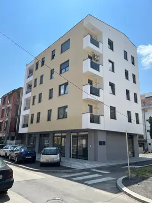 a building with cars parked in a parking lot at Apartmani Kastel 2 in Banja Luka
