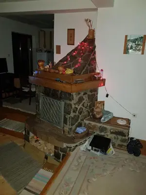 a living room with a stone fireplace with christmas lights at Ponijeri in Kakanj