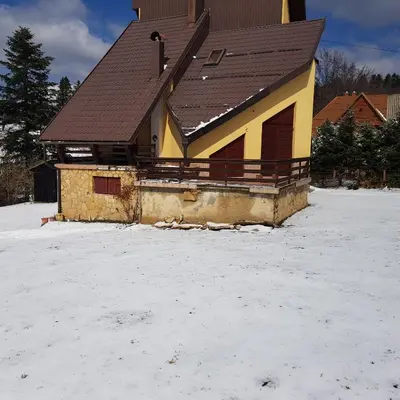 a house with a brown roof in the snow at Ponijeri in Kakanj