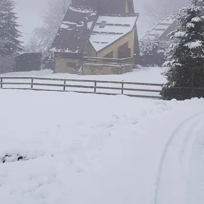 a snow covered yard with a fence and a house at Ponijeri in Kakanj