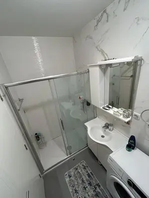 a white bathroom with a shower and a sink at Apartman Greenville Banja Luka in Banja Luka