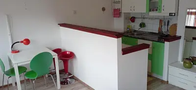 a kitchen with a counter and some green chairs at Jukan Apartman in Tuzla