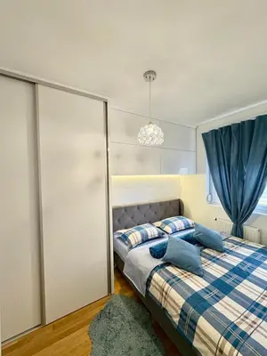 a bedroom with a bed with blue pillows at Apartman Sanja in Doboj