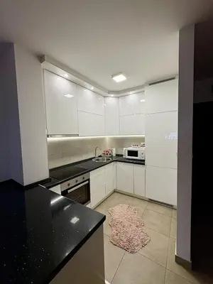 a kitchen with white cabinets and a rug on the floor at Apartman Sanja in Doboj