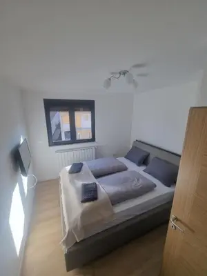 a bedroom with a bed with blue pillows and a window at Apartman Veni in Zenica