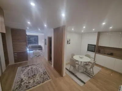a kitchen and living room with a table and chairs at Apartman Veni in Zenica