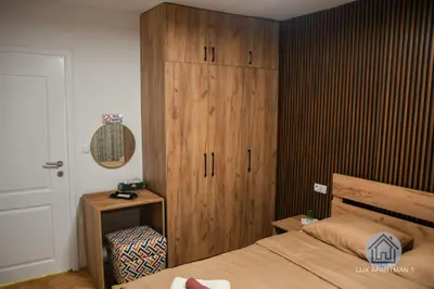 a bedroom with a wooden cabinet next to a bed at Lux Apartment 1 - Zenica in Zenica