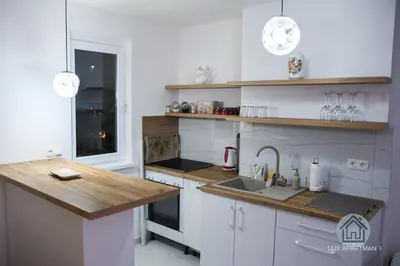 a kitchen with white cabinets and a wooden counter top at Lux Apartment 1 - Zenica in Zenica