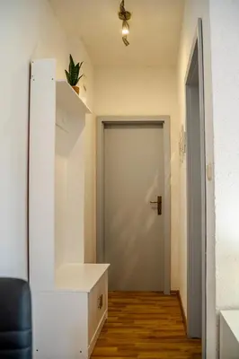 a hallway with a white door and a black chair at Apartman Gnječ Kupres in Kupres