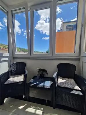 two chairs and a table in a room with windows at Apartman MARIA Livno in Livno