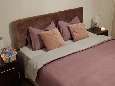 a bed with purple and pink pillows on it at Apartman MARIA Livno in Livno