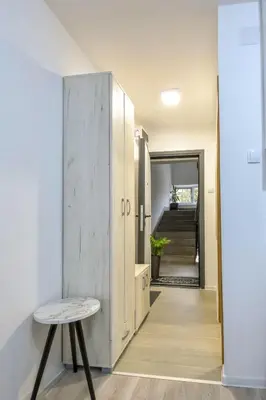 a hallway with a door and a table and a staircase at Apartman LILI centar in Banja Luka