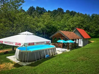 a couple of umbrellas and a swimming pool at Vikendica La Anja in Laktaši