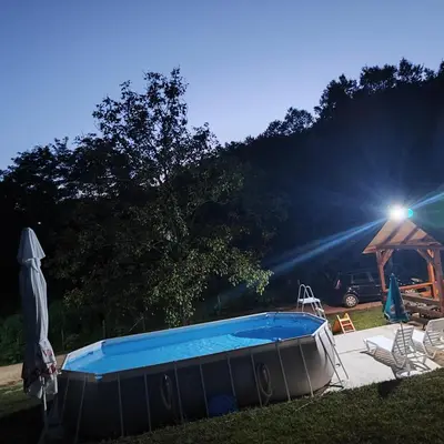 a swimming pool in a yard with a umbrella and chairs at Vikendica La Anja in Laktaši