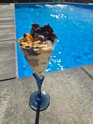 a dessert in a martini glass next to a pool at Apartmani City ES in Cazin
