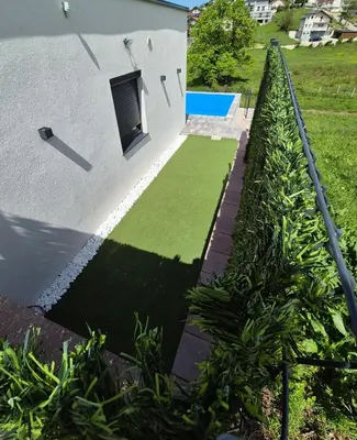 a house with a green lawn next to a building at Apartmani City ES in Cazin